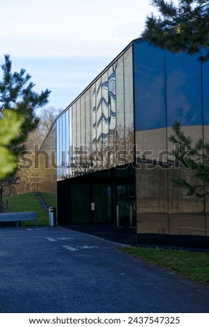 Diminishing perspective of glass facade of sport center at university campus with trees and scenic landscape at Swiss City of Zürich. Photo taken March 9th, 2024, Zurich, Switzerland. Royalty-Free Stock Photo #2437547325