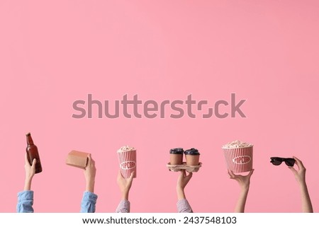 Many hands with buckets of popcorn, beer and coffee on pink background