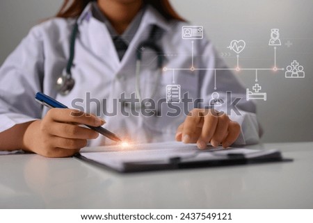 Female doctor with stethoscope recording healthcare treatment at desk Royalty-Free Stock Photo #2437549121