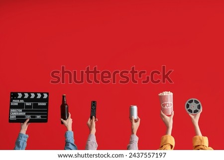 Many hands with bucket of popcorn, movie clapper and beer on red background