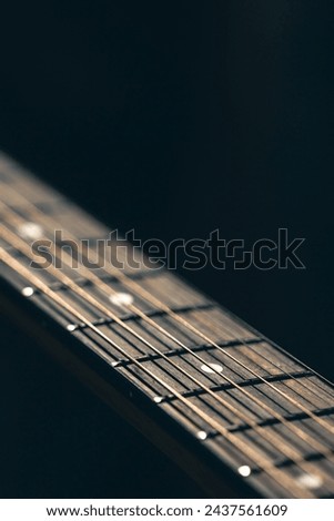 Part of an acoustic guitar, guitar fretboard on a black background. Royalty-Free Stock Photo #2437561609