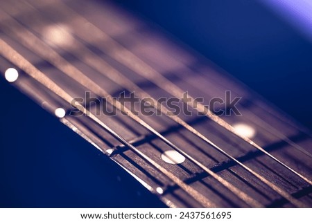 Part of an acoustic guitar, guitar fretboard on a black background. Royalty-Free Stock Photo #2437561695
