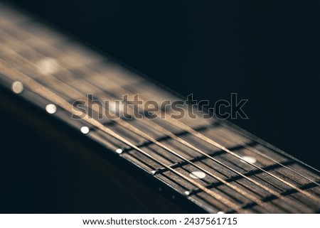 Part of an acoustic guitar, guitar fretboard on a black background. Royalty-Free Stock Photo #2437561715