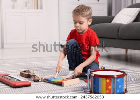 Little boy playing toy xylophone at home