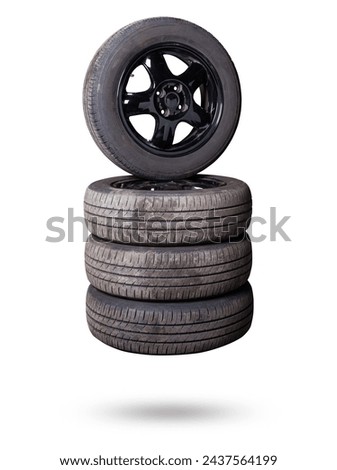 Automobile composition made up stack of tires and wheel with shiny black disc in the foreground against the background of cars in a car service before seasonal replacement or after breaking through. Royalty-Free Stock Photo #2437564199