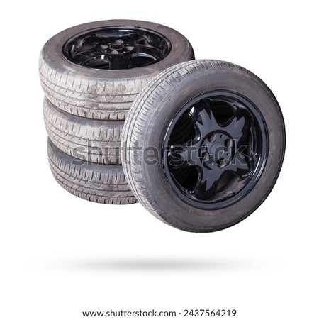 Automobile composition made up stack of tires and wheel with shiny black disc in the foreground against the background of cars in a car service before seasonal replacement or after breaking through. Royalty-Free Stock Photo #2437564219