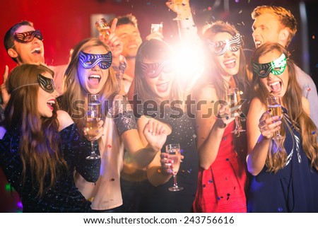 Friends in masquerade masks drinking champagne at the nightclub Royalty-Free Stock Photo #243756616