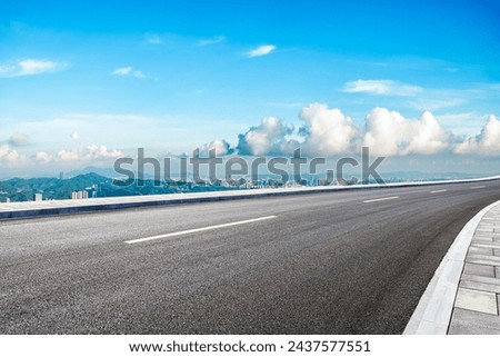 Asphalt highway road and green mountains with city skyline under blue sky