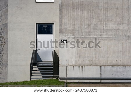 Concrete wall with stairway and door and white number 66 against black background on concrete wall at Swiss City of Zürich on a sunny winter morning. Photo taken March 9th, 2024, Zurich, Switzerland. Royalty-Free Stock Photo #2437580871