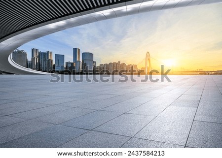 Empty square floor and pedestrian bridge with modern city buildings at sunrise in Guangzhou