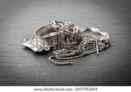 Pile of old scrap silver material jewellery, rings, pendants, chain necklaces, earrings. Scrap silver objects recycle concept. Royalty-Free Stock Photo #2437592693