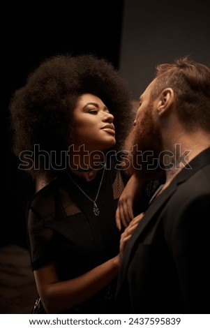 african american woman with curly hair in dress seducing tattooed boyfriend with beard, date night Royalty-Free Stock Photo #2437595839