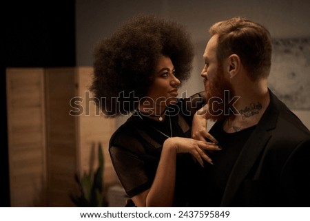 african american woman with curly hair in dress seducing tattooed boyfriend with beard, date night Royalty-Free Stock Photo #2437595849