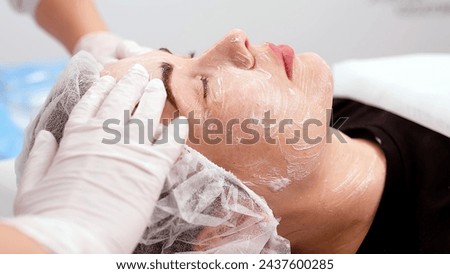 Side view portrait of young attractive woman on procedure for improvements skin. Concept of special masks and creams for moisturizing and improving the skin. Royalty-Free Stock Photo #2437600285