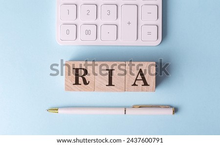 RIA on a wooden cubes with pen and calculator, financial concept