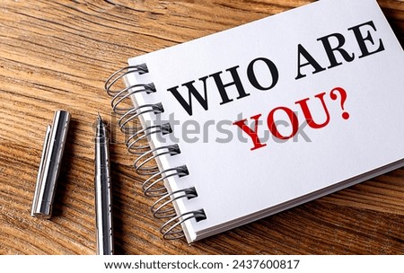 WHO ARE YOU text on a notebook with pen on wooden background