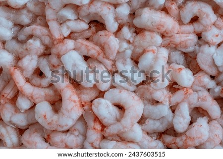 Lots of frozen shrimp for background use, close up, top view. Seafood on the counter. Fish market. Peeled boiled shrimps