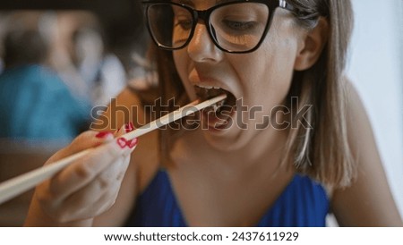 At a modern restaurant, a beautiful hispanic woman in glasses relishes her gourmet beef meal, gripping chopsticks with finesse. healthy, delicious japanese cuisine becomes her lifestyle delight. Royalty-Free Stock Photo #2437611929