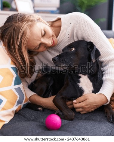 Young blonde woman hugging dog sitting on sofa at home