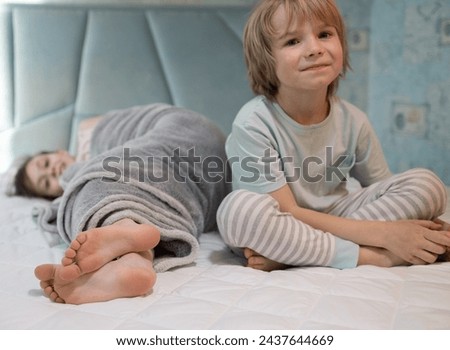 Two barefoot children in pajamas, brother and sister, play on bed at home. children's morning or evening family pampering. Cheerful childhood of offspring, cozy rest. selective focus Royalty-Free Stock Photo #2437644669