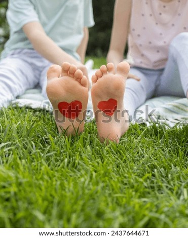 close-up on the bare feet of two children drawing red hearts. Cheerful childhood, childish love. positive atmosphere, summer weather. tender feelings, friendship day. unity. joyful mood Royalty-Free Stock Photo #2437644671