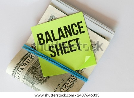 A yellow sticky note with Balance Sheet written on it placed on a stack of one hundred dollar bills secured by a blue rubber band, representing financial concept and wealth management.