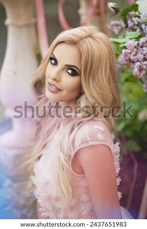 A beautiful young Caucasian smiling happy girl with professional makeup in a delicate pink dress .spring photo