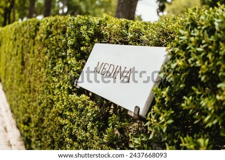 "Medina" sign in trimmed bushes in a park