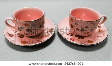 a pairs of cup with Christmas ornaments art. Which contains images trees, flowers, mittens, snowflakes, Christmas toys, penguin and Christmas crackers in cartoons style.