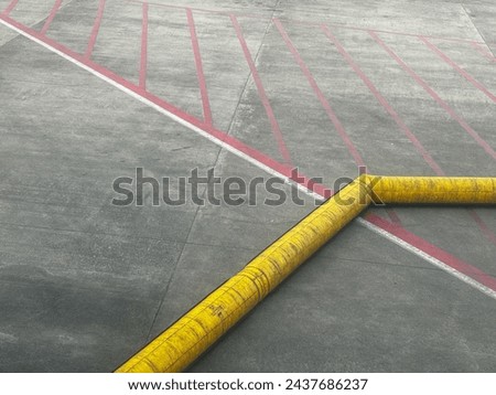 A yellow and red line on a parking lot. The yellow line is a caution tape that is placed on the ground