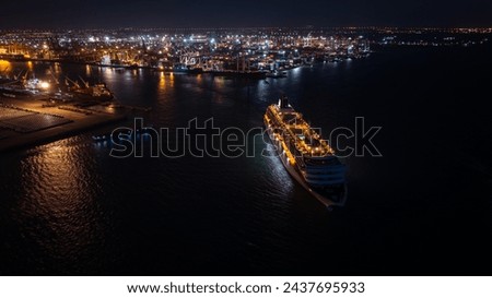 luxury large cruise ship departing from Laem Chabang Port at night.  want to use low shutter speed to see movement of the ship. blue tone and over lighting scene photography aerial view.