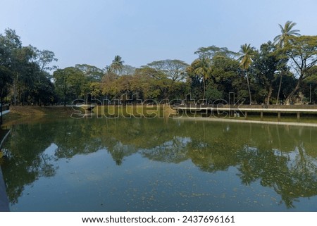 Beautiful Ramna park with lake, trees and side walkway. Dhaka, Bangladesh Royalty-Free Stock Photo #2437696161