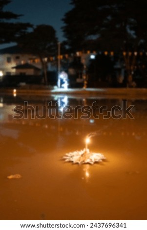 Blur picture of a lights of Kratong make from paper floating alone on a pond during in Loy Kratong festival night in Thailand