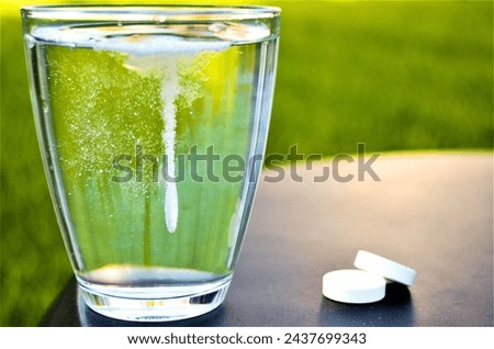 Dissolving aspirin pill on glass of water on green background with writing space