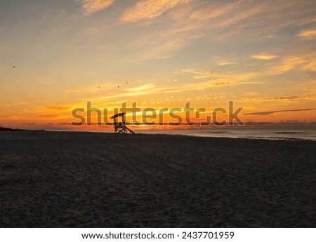 Sunrise at the beach behind a silhouette of a lifeguard seat