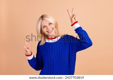 Portrait of funky pretty aged lady beaming smile good mood demonstrate v-sign isolated on beige color background