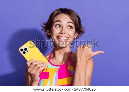 Photo of young toothy beaming smile optimistic lady using smartphone direct finger empty space isolated on purple color background