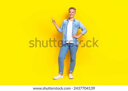 Full size photo of pretty young girl point look interested empty space wear trendy jeans outfit isolated on yellow color background