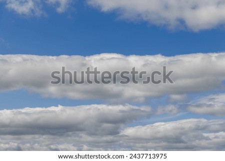 Sky with layers of cumulus clouds, illuminated by a soft, light blue radiance. This captivating backdrop extends towards the horizon, providing a serene and dynamic canvas or sky replacements
