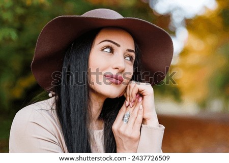 Autumn allure. Closeup of young woman in a beige coat and hat enjoying the vibrant colors of the season.