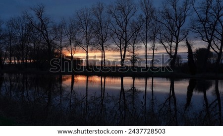 Reflections of trees in water at sunset. The picture is taken at a canal called  'Damsche Vaart' in Sluis, the Netherlands