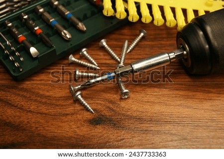 Dowels, screws, screwdriver, bit set. Tools and fasteners on a wooden surface. High quality photo