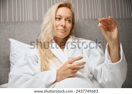 Pleased lady preparing to take medicament in her bedchamber Royalty-Free Stock Photo #2437749683