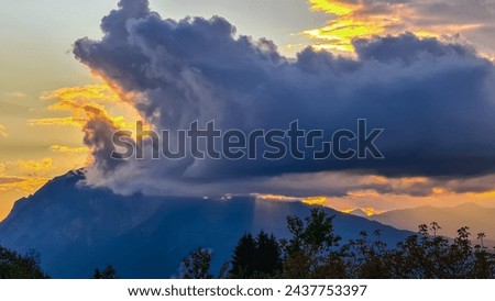 Scenic sunset view of iconic mountain peak Dobratsch seen from Altfinkenstein at Baumgartnerhoehe, Carinthia, Austria. Massive cloud formation. Overlooking Villach area surrounded by Austrian Alps Royalty-Free Stock Photo #2437753397