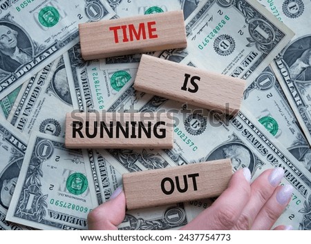 Time is running out symbol. Concept words Time is running out on wooden blocks. Beautiful dollar background. Businessman hand. Business and Time concept. Copy space.