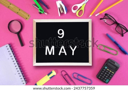 May 9 written in chalk on black board. Calendar date 9th of May on chalkboard on pink blurred school stationery background. Event schedule date. School, study, education concept. Month of spring.