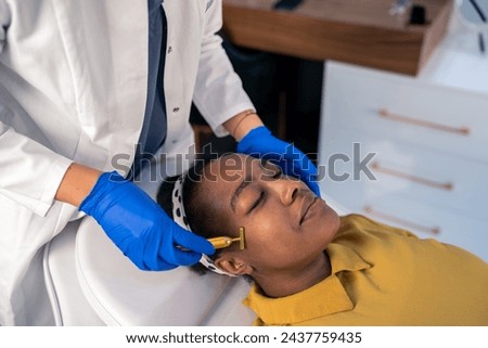 Beautician removing wrinkles on the face of a female costumer with face golden roller massager.