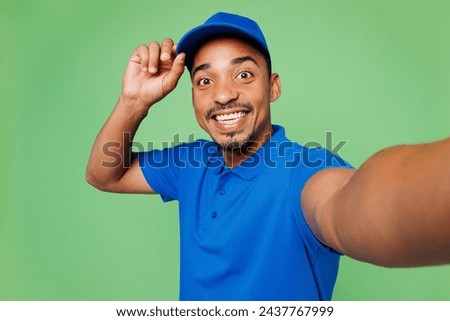 Close up professional delivery guy employee man wears blue cap t-shirt uniform workwear work as dealer courier do selfie shot on mobile cell phone isolated on plain green background. Service concept