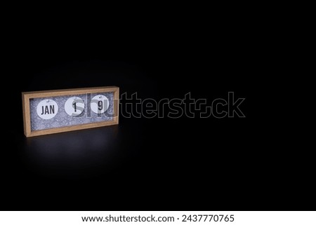 A wooden calendar block showing the date January 19th on a dark black background, save the date or date of event concept