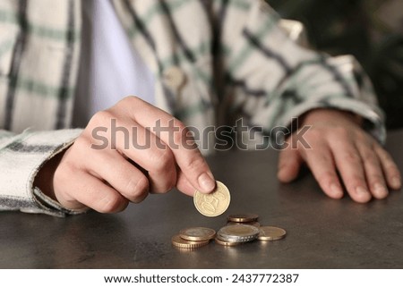 Poor woman counting coins at grey table indoors, closeup